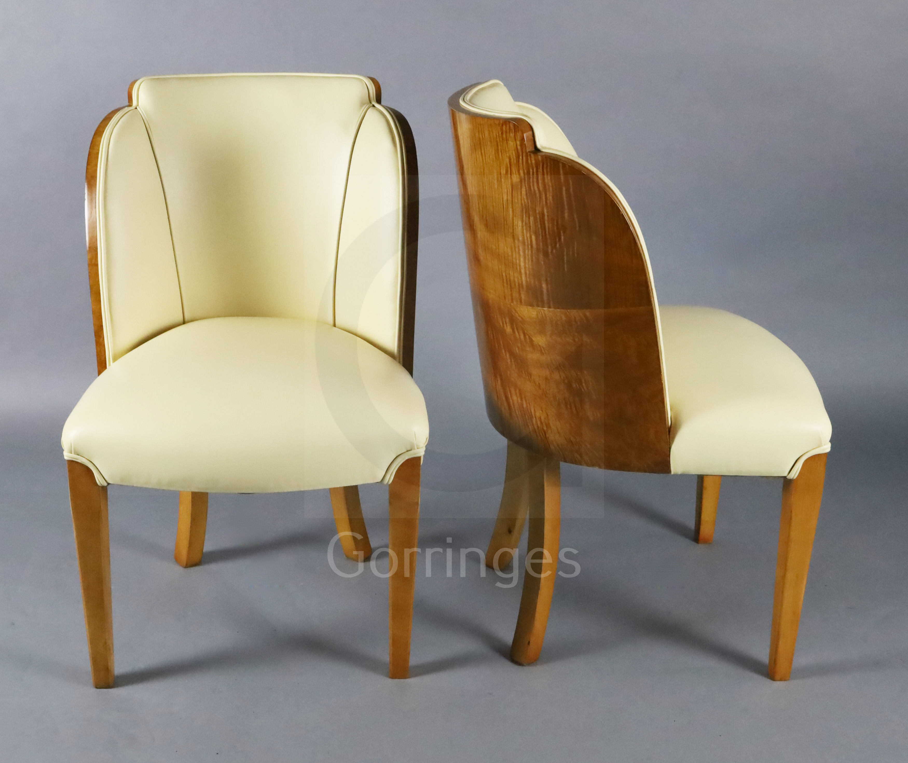 A set of six Art Deco tiger maple cloud back dining chairs, with cream leather upholstery on