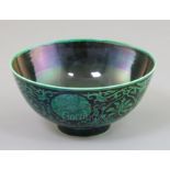 A Chinese green and black enamelled bowl, Qianlong mark, painted with lotus flowers and scrolling