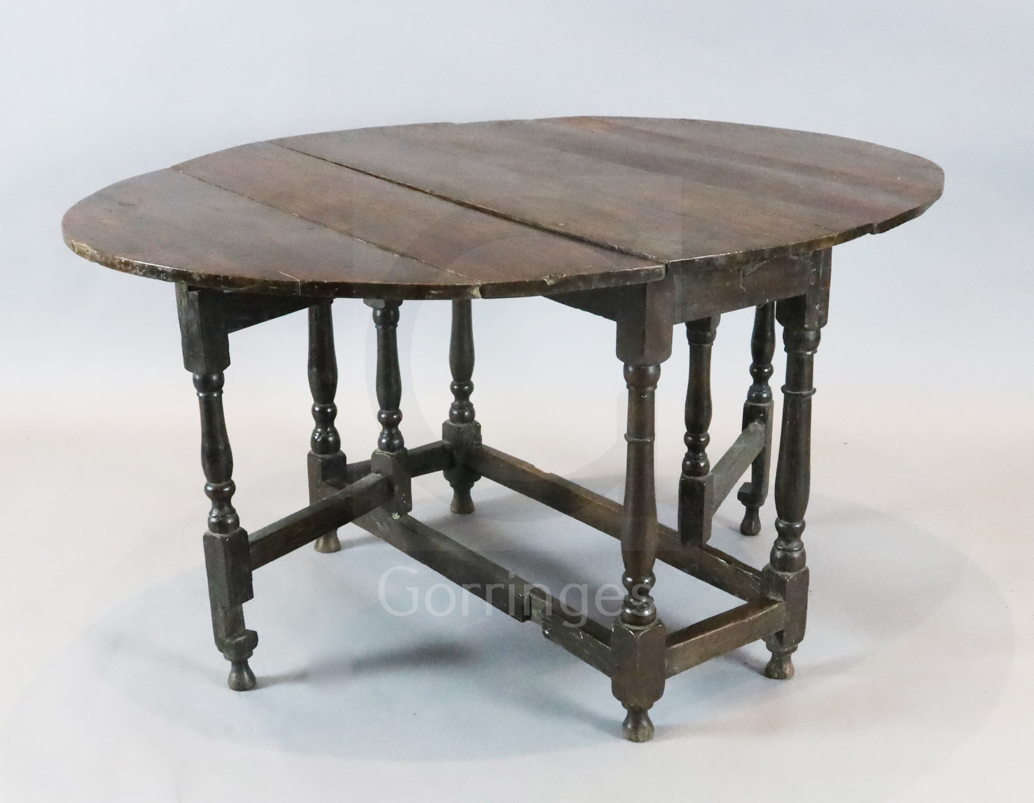 An early 18th century oak oval topped gateleg dining table, with turned and squared underframe,