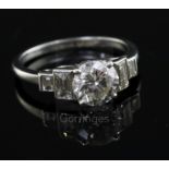 A platinum and single stone diamond ring with baguette cut diamond set stepped shoulders, the