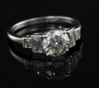 A platinum and single stone diamond ring with baguette cut diamond set stepped shoulders, the