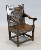 A mid 17th century jointed oak Wainscot elbow chair, with lozenge and roundel carved back panel,