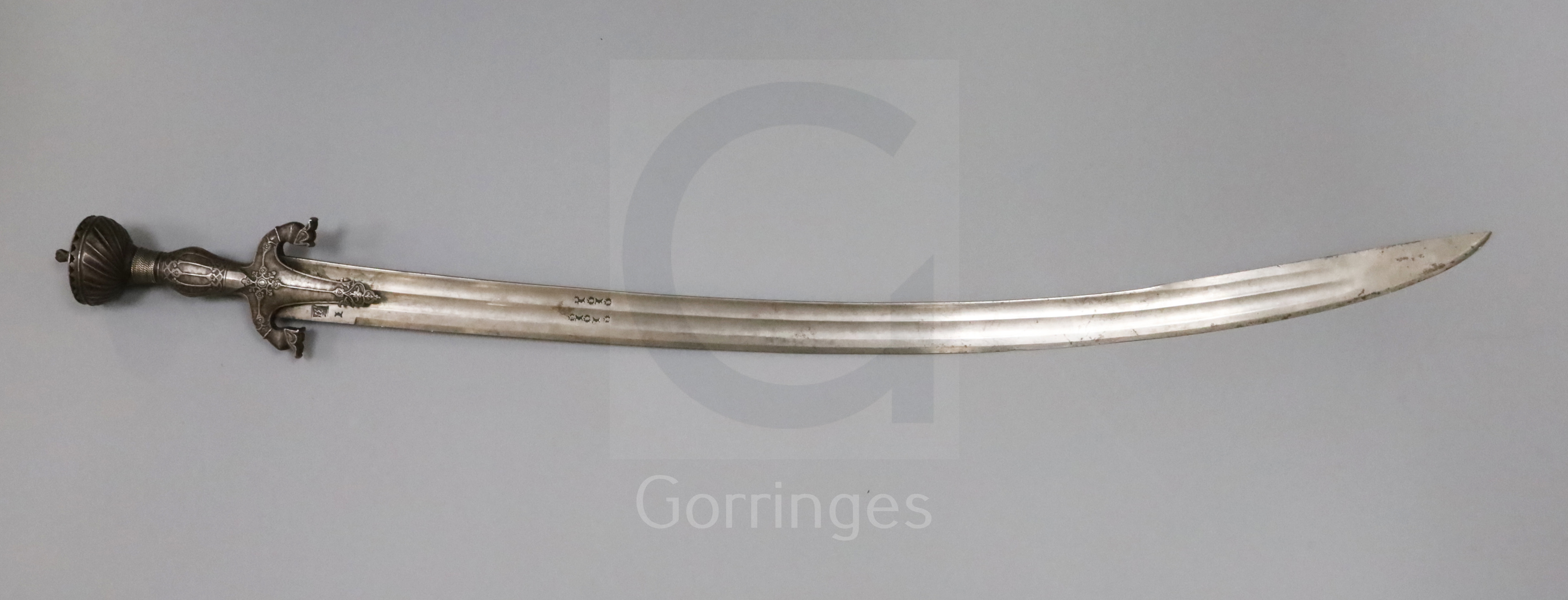 An Indian steel handled tulwar, with engraved and stamped blade, the hilt decorated with stylised