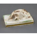 A Rockingham porcelain figure of a recumbent cocker spaniel, c.1830, on a rectangular green patch