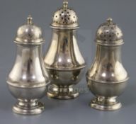 A suite of three early George II Scottish silver baluster pepperettes by James Mitchelson I,