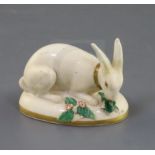 A Rockingham porcelain figure of a rabbit, c.1830, in cream and gilt eating green leaves, on an oval