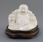 A Chinese blanc-de-chine figure of Budai, 19th century, seated and holding a peach in his right