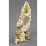 A Japanese ivory okimono of a Yamabushi Tengu, Meiji period, blowing on a conch shell, a monkey at