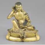 A Sino-Tibetan gilt bronze seated figure of Milarepa, his right hand cupped behind his ear,