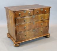 An early 18th century inlaid walnut chest of two short and three graduated long drawers, on bun