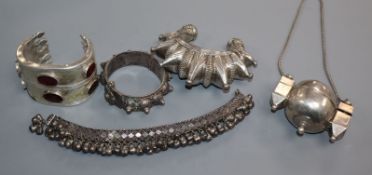 Two Eastern white metal open bangles, a bracelet with bells, one other hinge bangle and a pill?