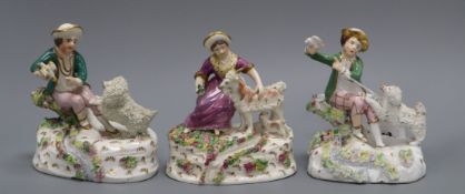 Two Staffordshire porcelain groups of a boy and a poodle and the companion group of a girl feeding a