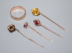 A yellow metal wedding band and four assorted stick pins, including gem set.