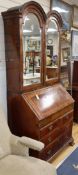 A George I featherbanded walnut bureau bookcase, with twin domed top and two mirrored doors over