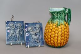 A Minton Majolica pineapple jug and two putti blue-glazed tiles tallest 12.5cm