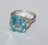 A white metal and blue zircon ring with diamond set shoulders (stone chip), size K.