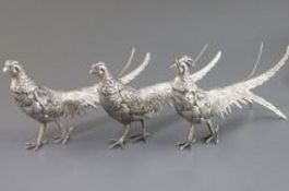 A suite of 3 Egyptian white metal freestanding model pheasants, comprising a cock and two hens, cock