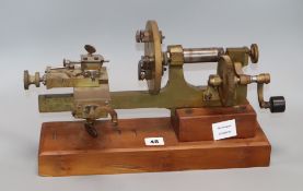 An early 20th century brass and steel clockmaker's lathe, on mahogany plinth