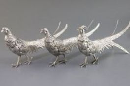 A suite of 3 Egyptian white metal free standing model pheasants, comprising a cock and two hens,