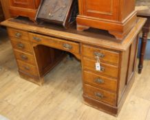 A late Victorian oak kneehole desk, fitted nine small drawers W.130cm