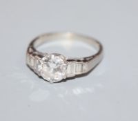 A white metal and single stone diamond ring, with graduated baguette cut diamond set shoulders,