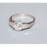 A white metal and single stone diamond ring, with graduated baguette cut diamond set shoulders,