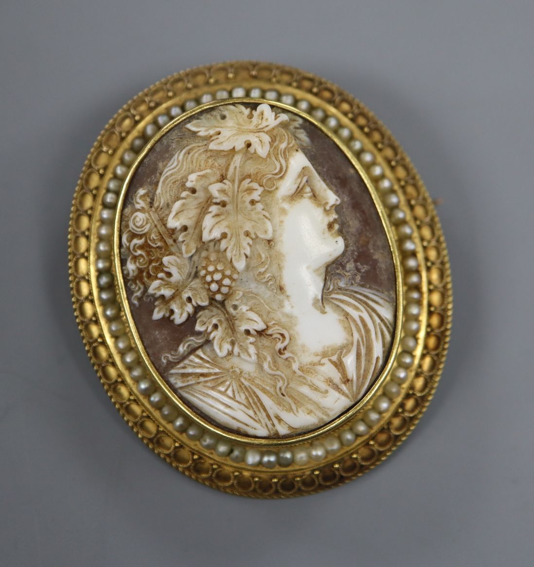 A yellow metal (tests as 18ct) and seed pearl mounted oval cameo brooch, carved with the bust of a