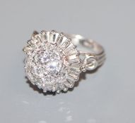An ornate white metal, baguette and round cut diamond set cluster dress ring, size K.
