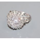 An ornate white metal, baguette and round cut diamond set cluster dress ring, size K.