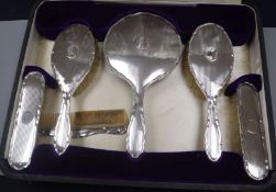 A cased George V engine turned silver six piece dressing table set.