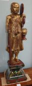 A Tibetan carved giltwood figure of a monk on mirrored plinth base
