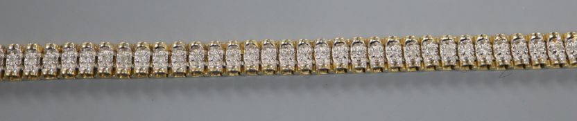 A modern 14k yellow metal and diamond set line bracelet, 18cm.
