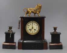 A rouge and black marble clock garniture, the clock of architectural form with enamelled Arabic dial