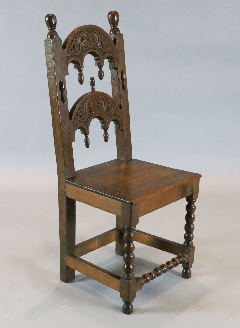 A 17th century Derbyshire oak side chair, with carved and turned arched back and solid seat on