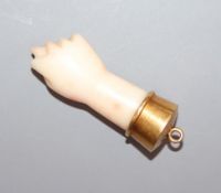 A yellow metal mounted coral pendant, modelled as a closed fist with protruding thumb, overall