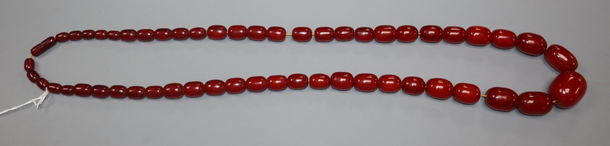 A single strand graduated simulated cherry amber necklace, gross weight 119 grams, approx. 90cm.