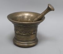 A 17th century bronze mortar inverted bell shape with scroll and shell design, a matching pestle,