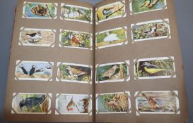 An album of cigarette cards, including Players Cricketers 1930 and 1934 (50), Cage and Aviary Birds,