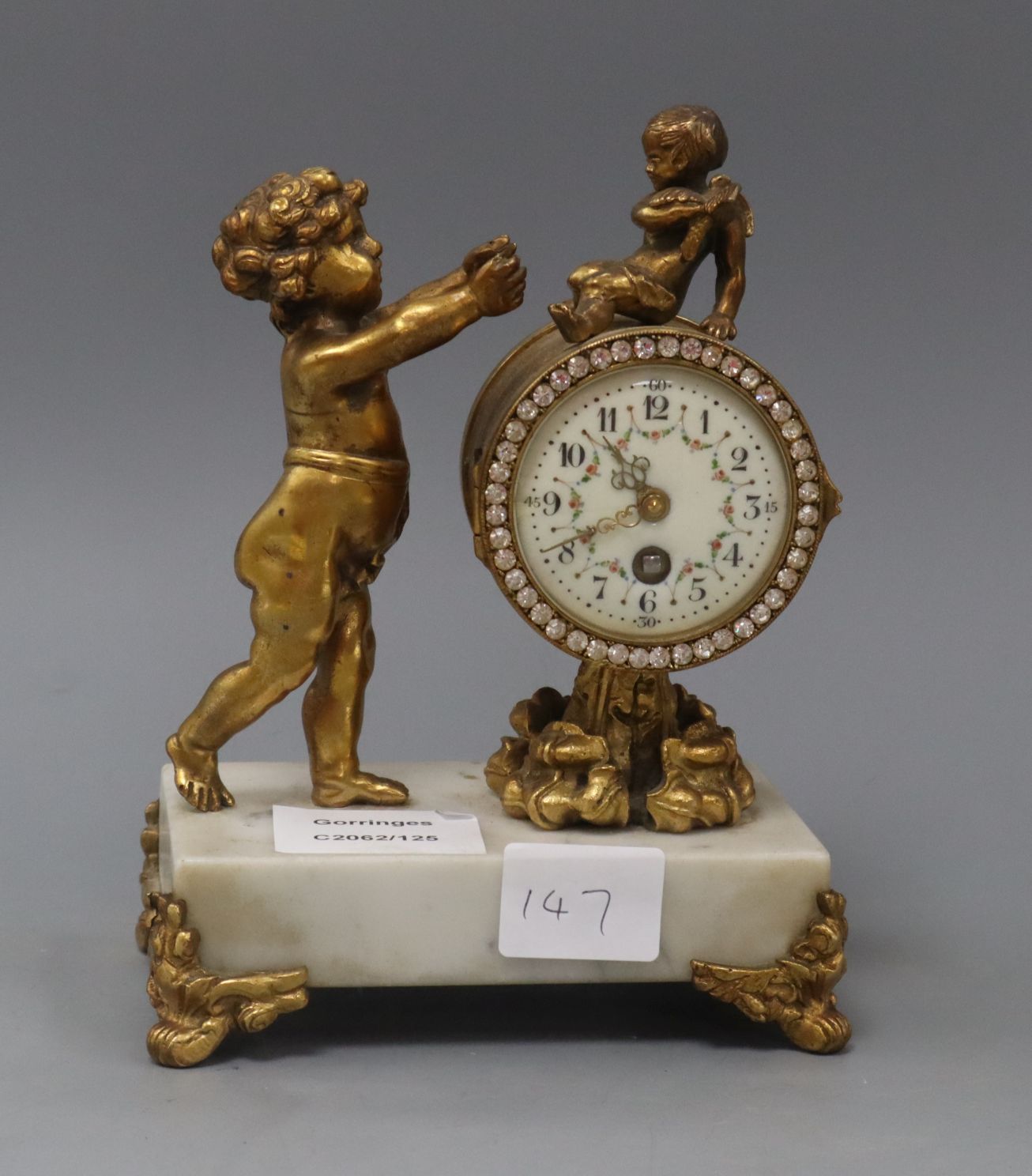 A gilt metal and marble figural mantel timepiece