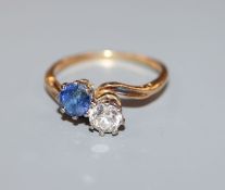 A mid 20th century yellow metal, two stone sapphire and diamond crossover ring, size L.
