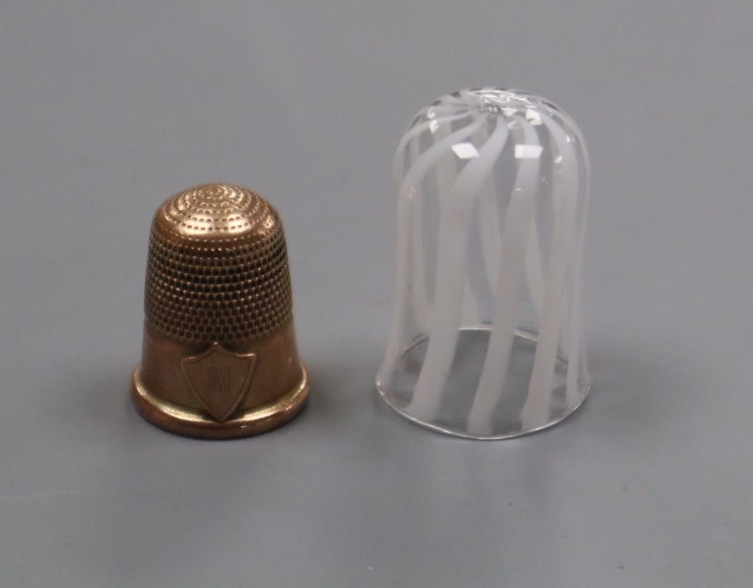 A 9ct yellow metal thimble and a Nailsea glass thimble.