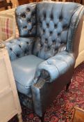 A reproduction armchair upholstered in buttoned blue leather
