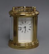 A miniature oval gilt brass carriage clock with white enamel Roman dial