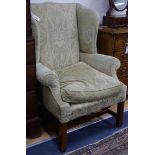 A Georgian style mahogany shaped wing armchair with green upholstery, square supports and H-