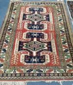 A Caucasian red ground rug with two hooked medallions and nine-row border 280 x 187cm