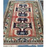 A Caucasian red ground rug with two hooked medallions and nine-row border 280 x 187cm