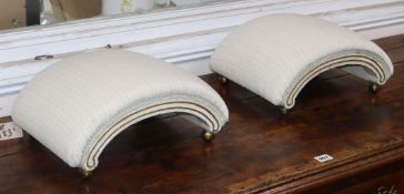 A pair of Regency footstools of arched-form, having painted and parcel-gilded moulded frames, on