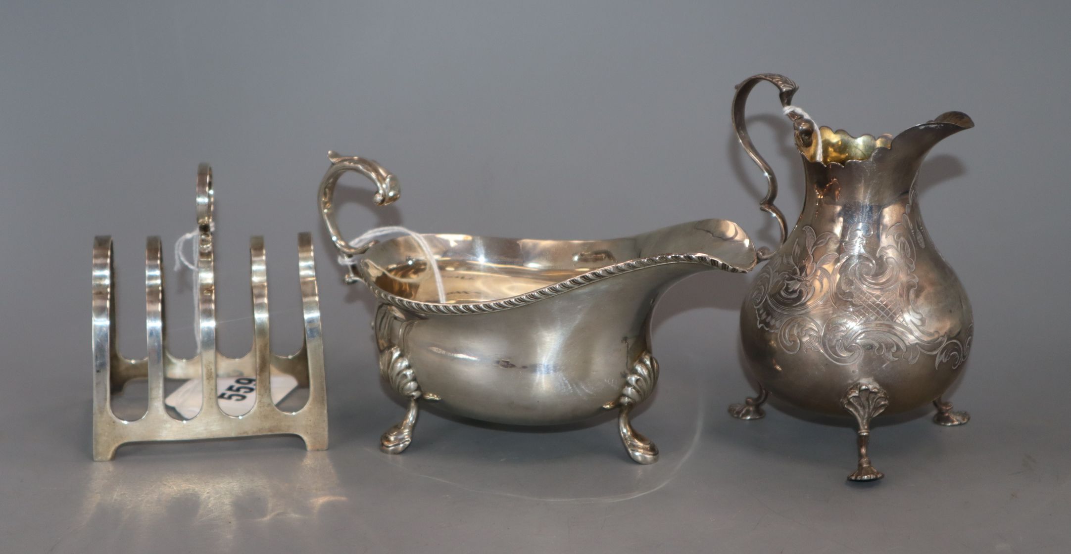 A Victorian engraved silver cream jug with scrolled handle and vacant cartouche, London 1856, a