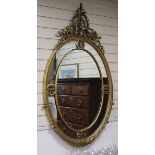 A George III style giltwood and gesso oval wall mirror, the leaf-wrapped frame having gilt