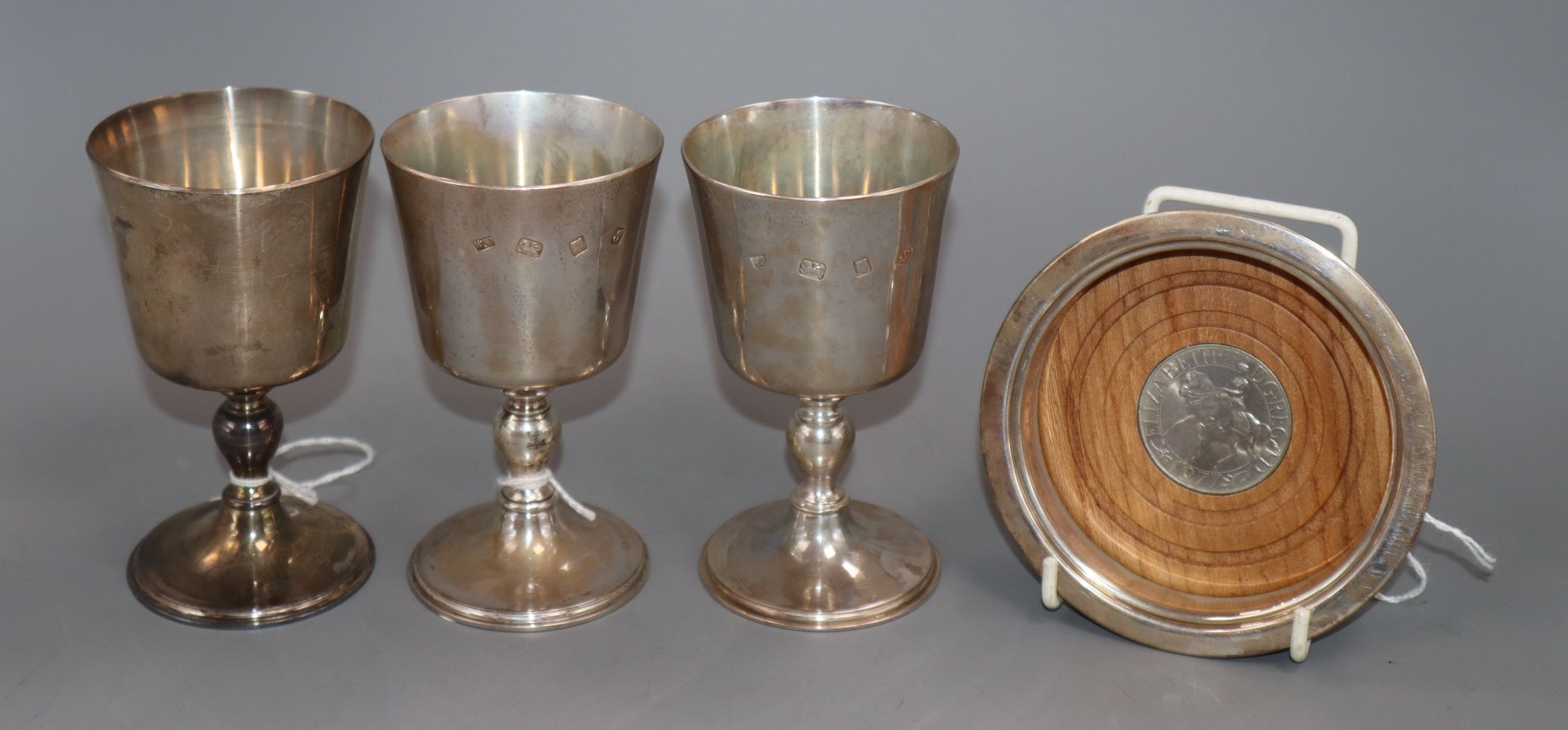 Three silver goblets by Mappin & Webb and a Merchant Taylors Company bottle coaster, 17oz (